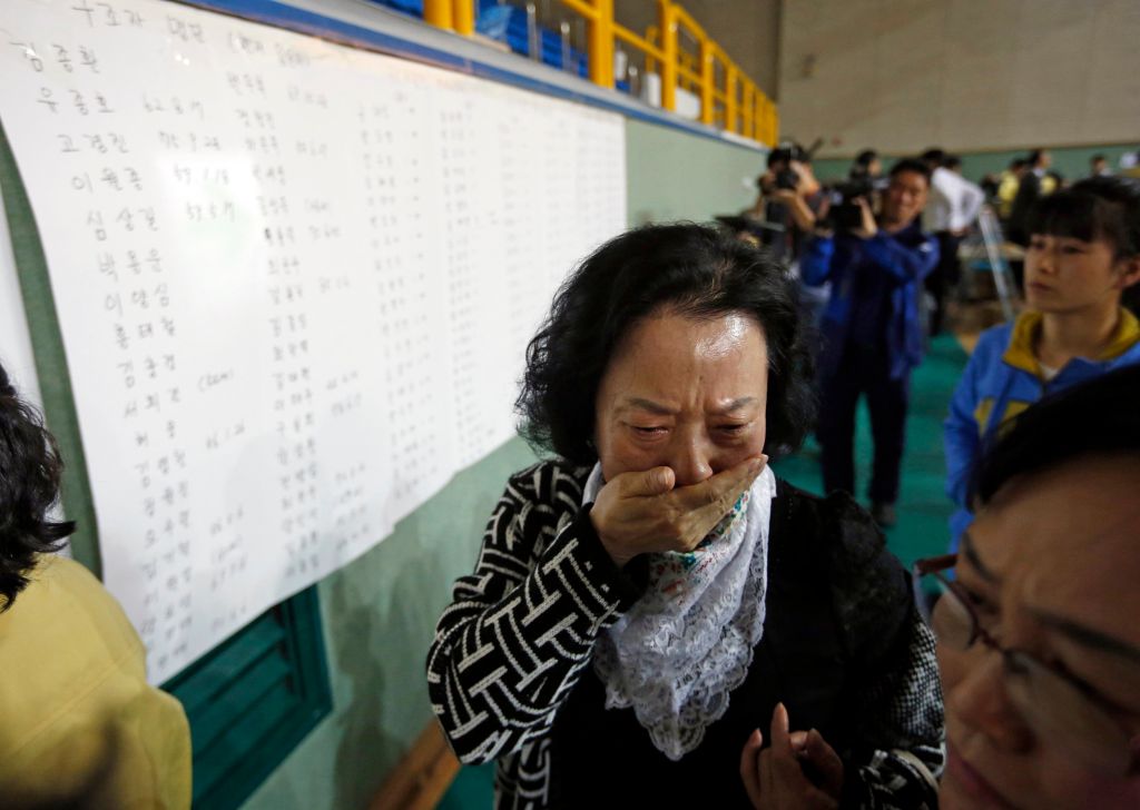 Image: The mother of a passenger who was on a sinking ferry reacts after finding her son's name in the survivors list in Jindo