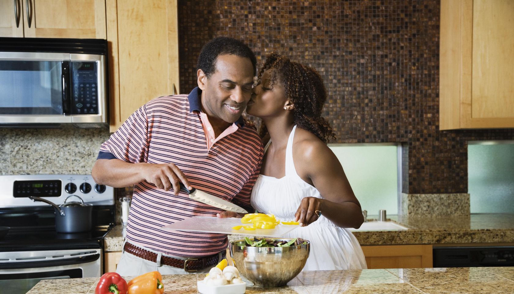 African couple fixing healthy meal in modern kitchen
