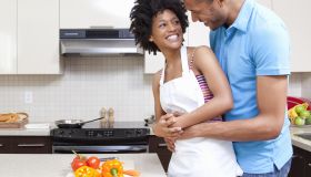 Man embracing woman preparing vegetables