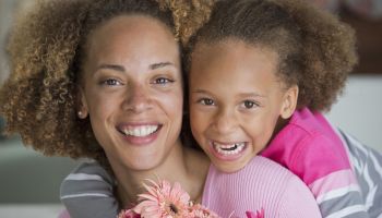 Black mother and daughter holding bouquet of flowers