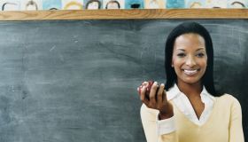 Portrait of a Teacher Standing in Front of a Blackboard Eating an Apple