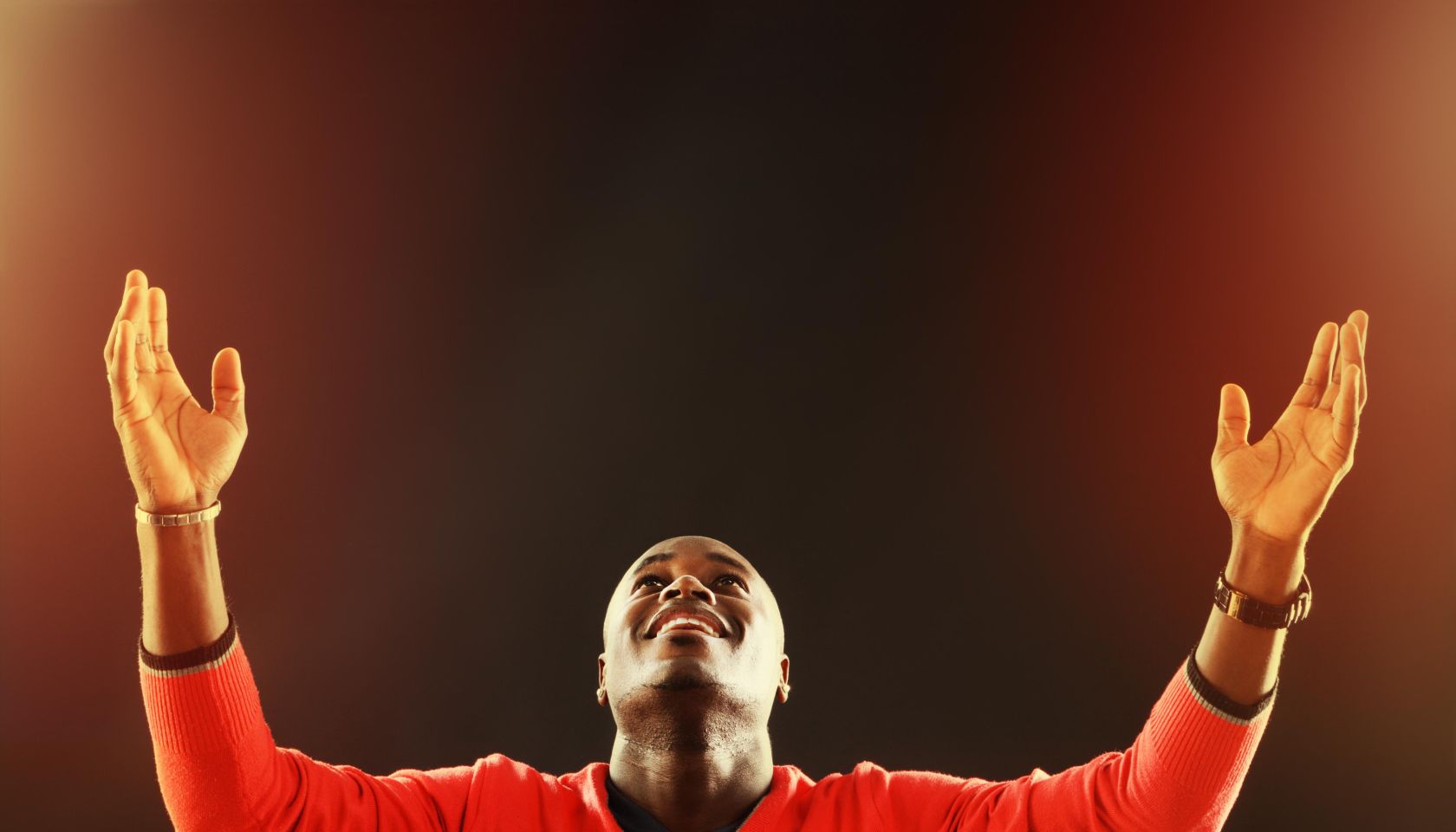 Inspired young man looks up, his hands raised in prayer