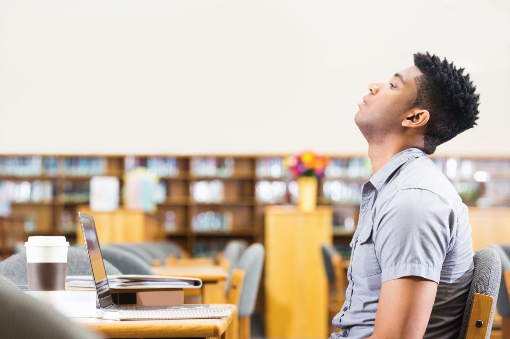 Tired or frustrated African American student studying late in library