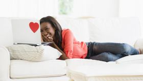 Black woman using laptop on sofa