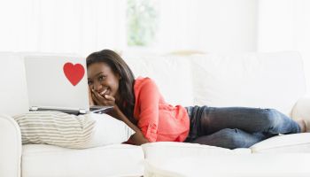 Black woman using laptop on sofa