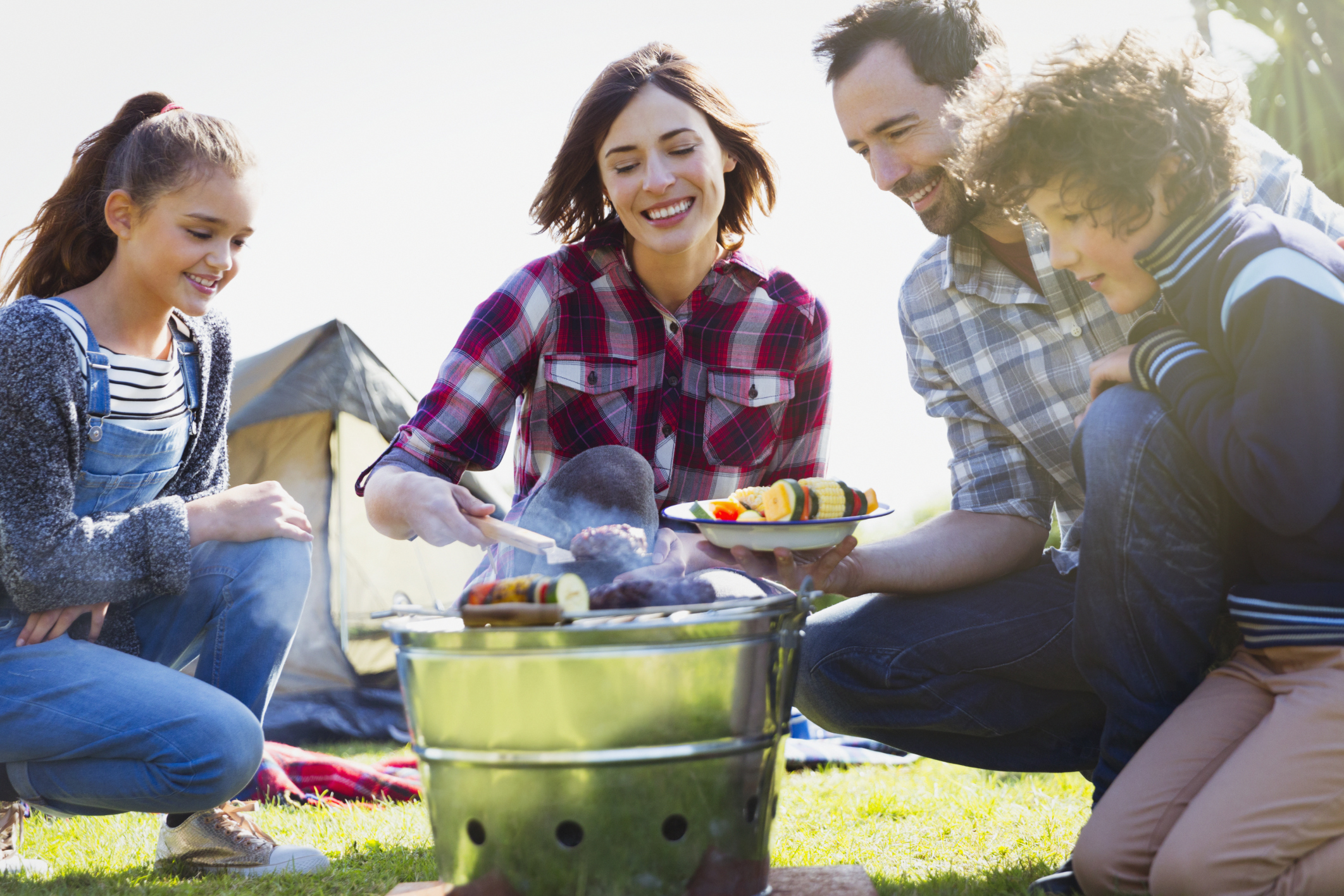 Family barbecuing at campsite grill