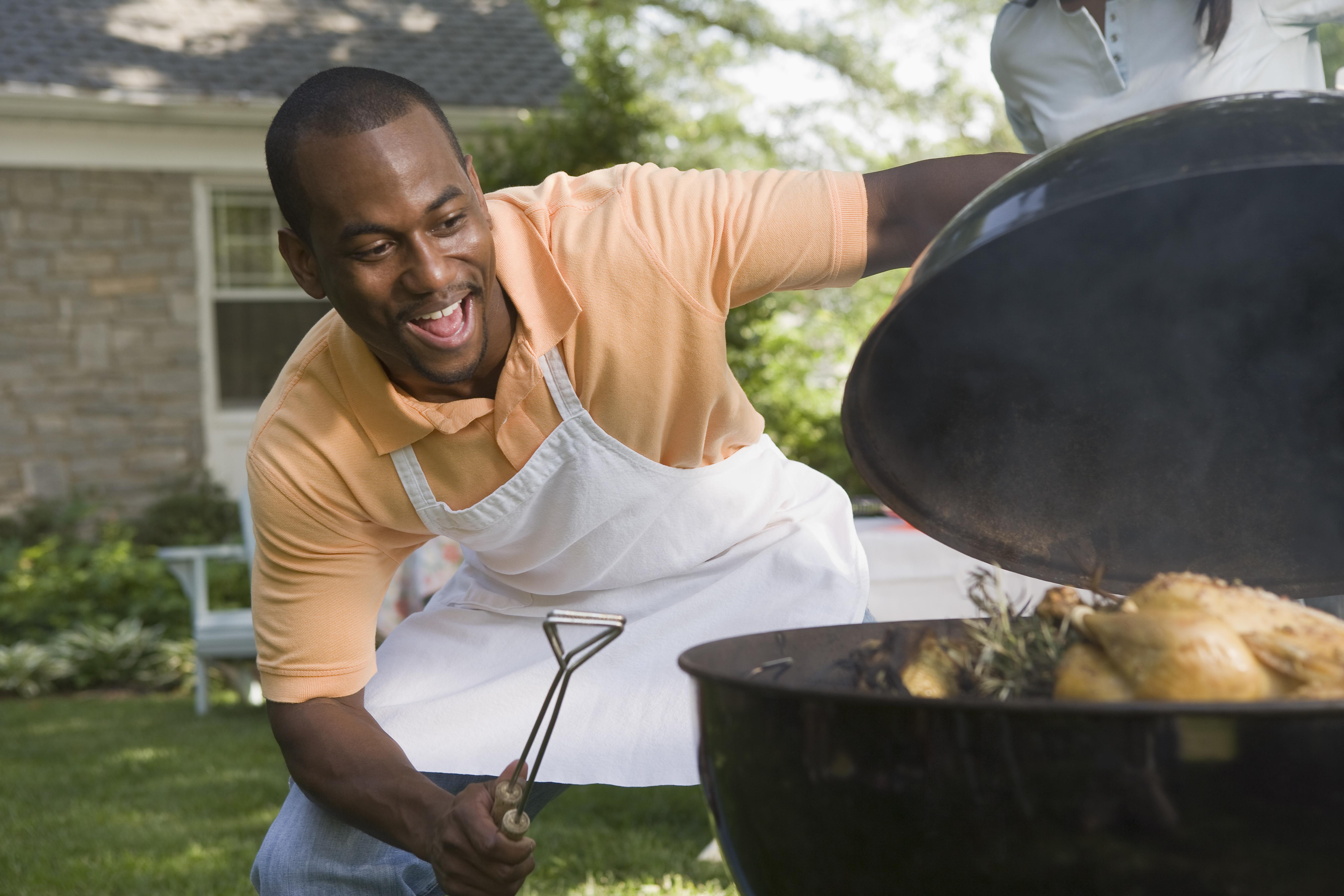 Smiling man cooking food on grill outdoors