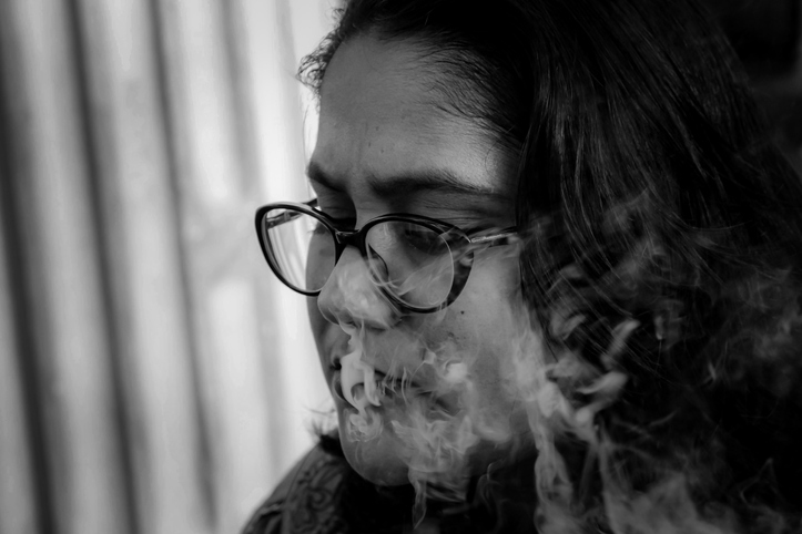 Close-Up Of Thoughtful Young Woman By Smoke At Home