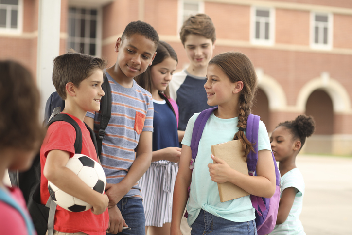 Group of school children, friends talking together on campus.