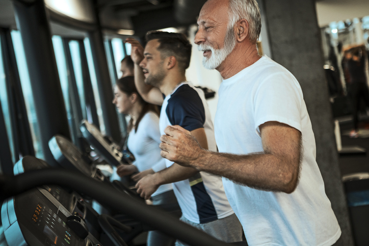 Senior man on a treadmill enjoin run in a gym