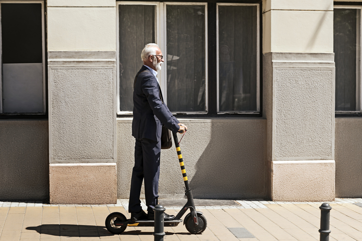 Senior Businessman riding a scooter in the city