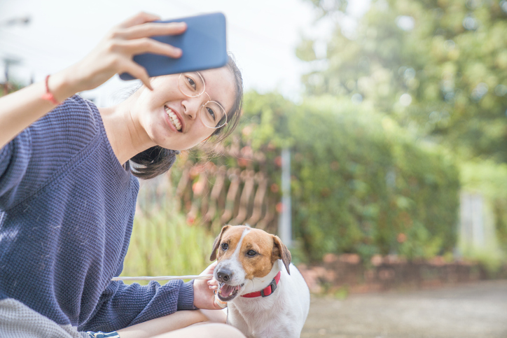 Asian teenage girl take Selfie playing with playful her pets Jack Russell Terrier dog at garden in summer morning