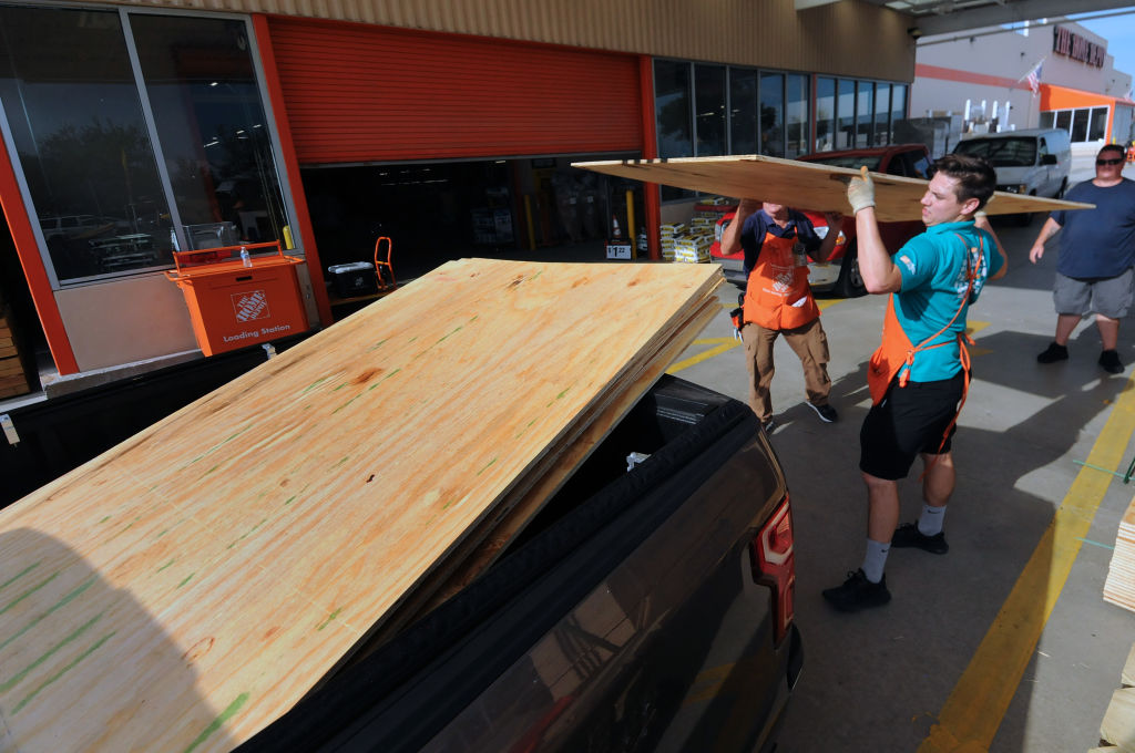 Workers load sheets of plywood into a customer's truck at a...