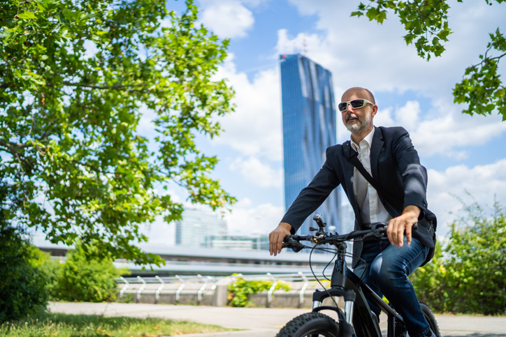 mature man on bicycle in city park