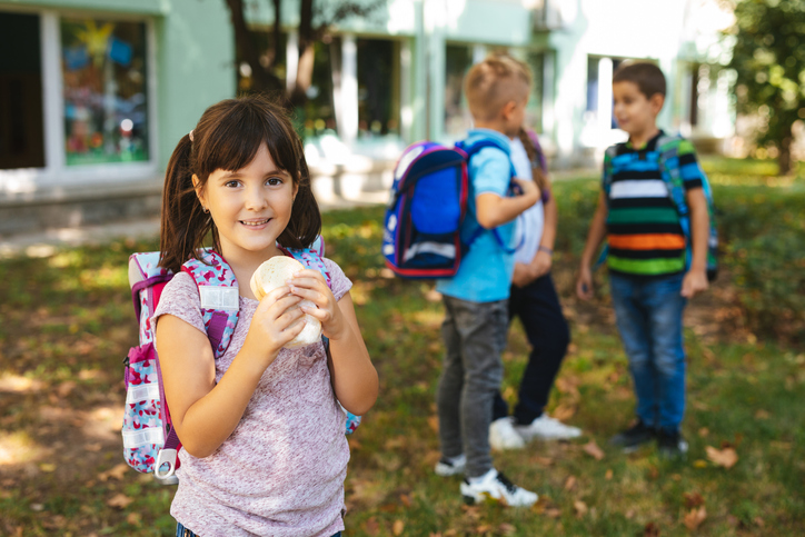 Little girl eating sandwich in a school yard