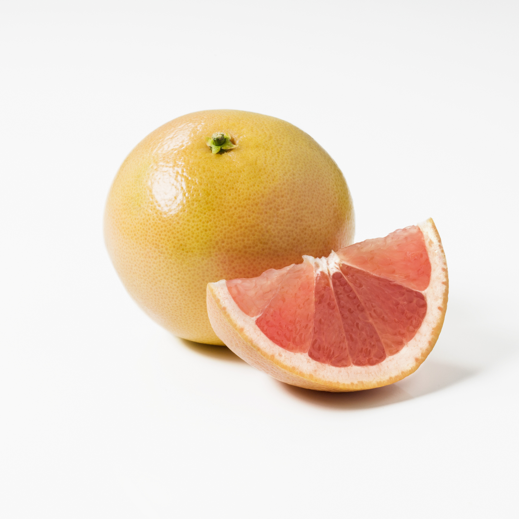 Whole grapefruit and a slice on a white background