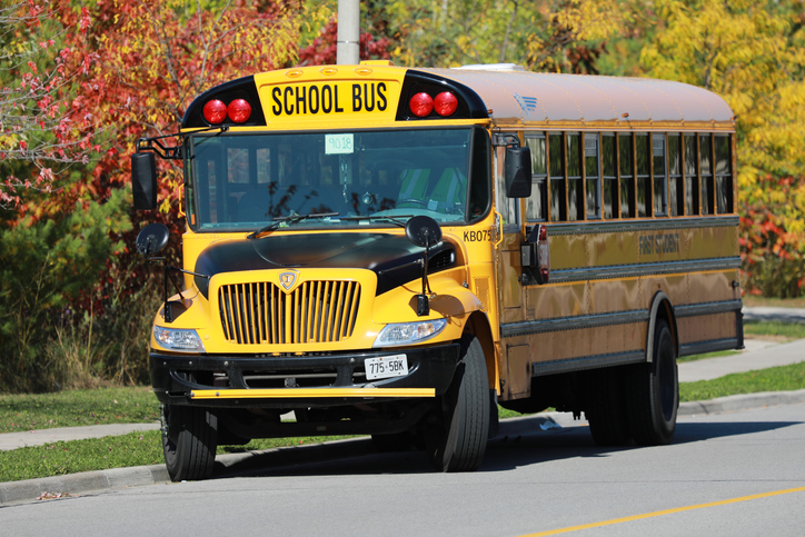 Yellow school bus on autumn background