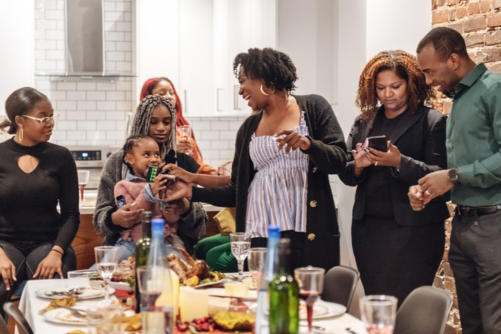 Multi-generation ethnic family having Thanksgiving dinner, doing karaoke