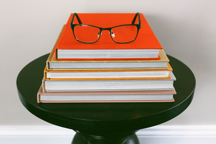 Stack of Books on Side Table with Reading Glasses on Top