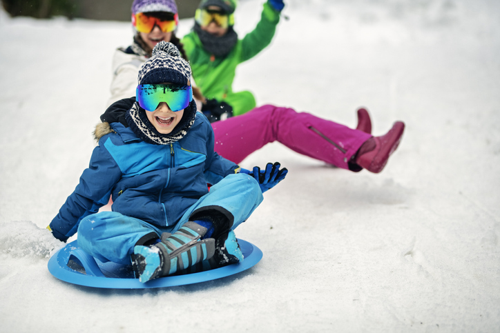 Three kids sledding in winter.