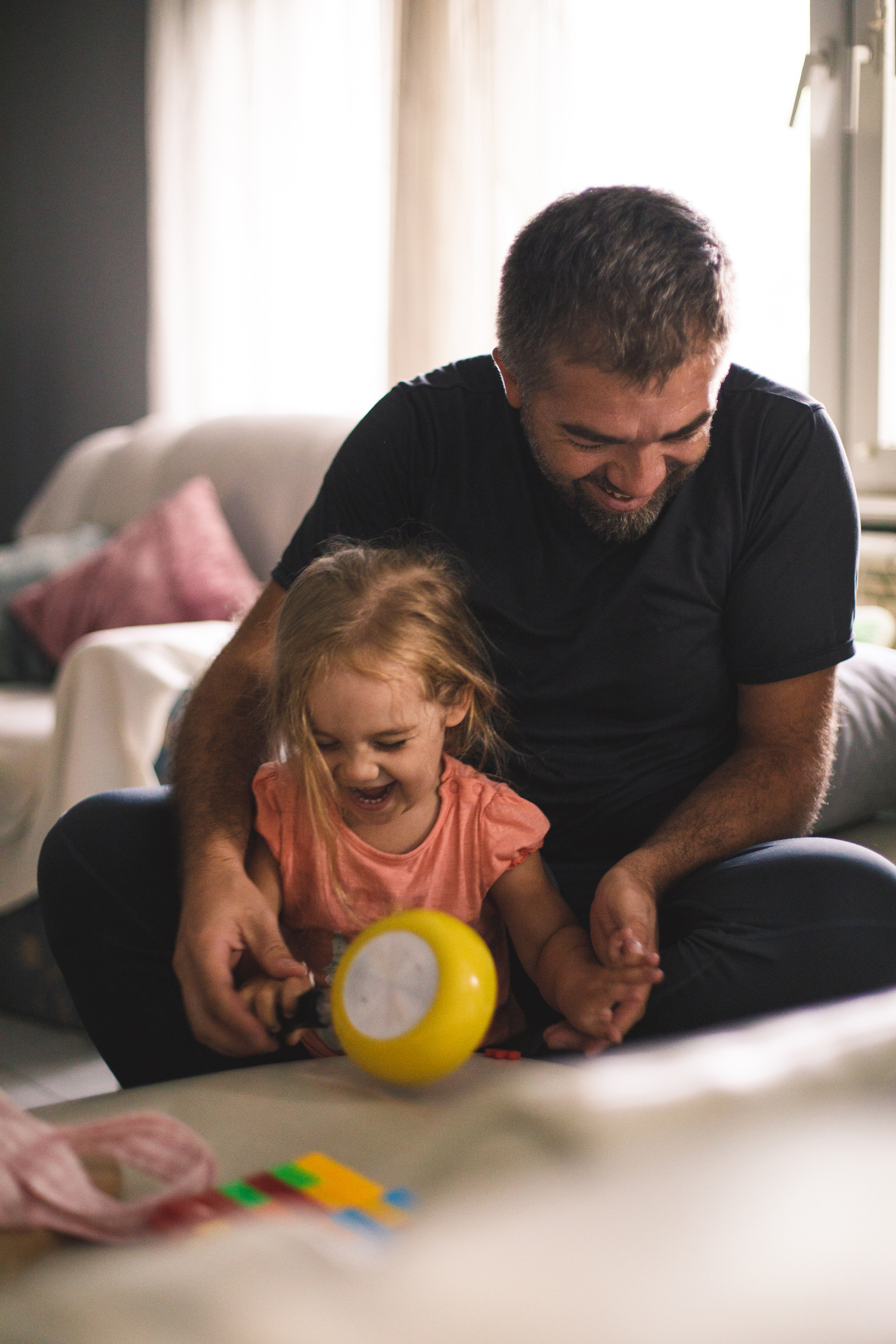 Joyful father and daughter having fun while playing with toys together