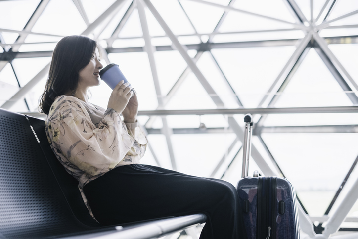 A tourist enjoy her coffee while waiting her flight in departure zone