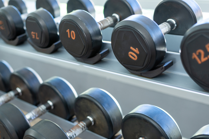 Rows of black metal dumbbells in the gym, selective focus.