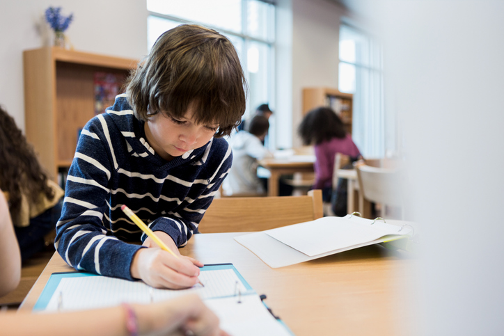 Schoolboy concentrates while working on assignment