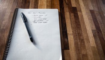 New year's resolution written on a notebook, and a pen on a wooden table
