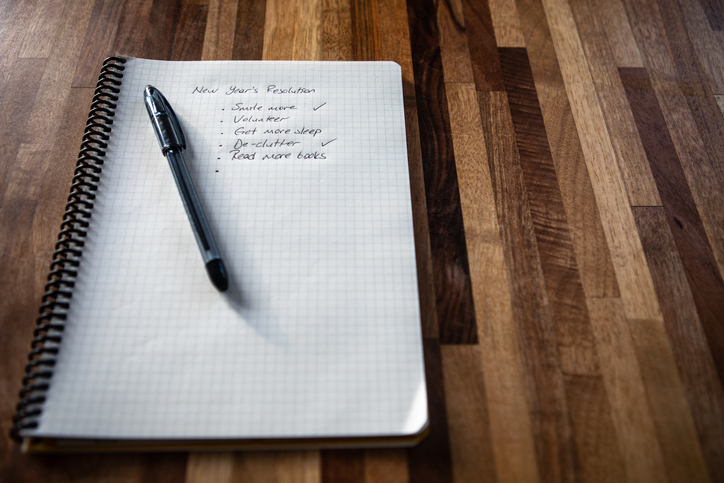 New year's resolution written on a notebook, and a pen on a wooden table