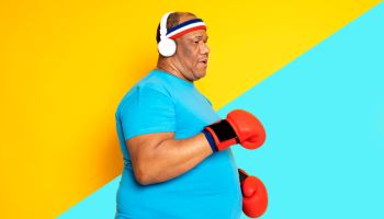 Overweight black man practices exercise and boxing and listens to music on his headphones