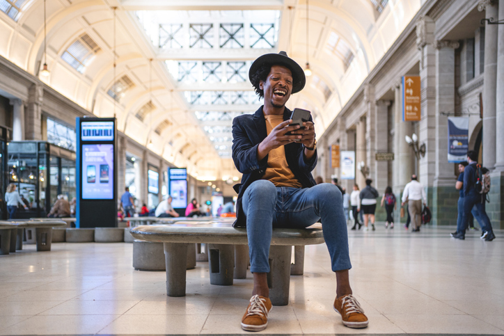Happy African American adult watching videos on his mobile phone