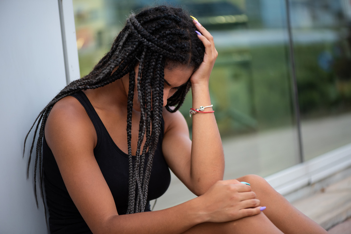Sad teen woman in deep sorrow sitting outside