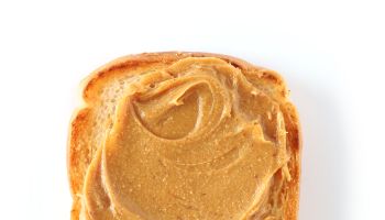 Close-Up Of Peanut Butter On Toasted Bread Over White Background