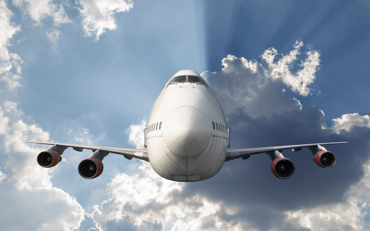 Passenger airplane flying above clouds at sunset.