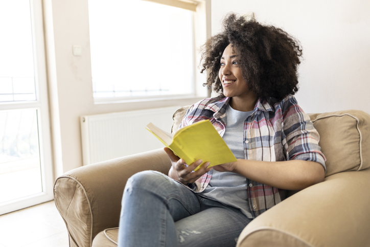 Smiling woman reading a book at home