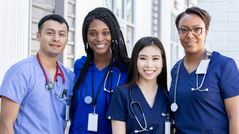 Diverse group of four nursing students standing together outdoors