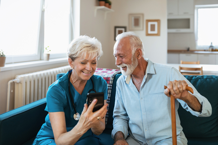 Mature nurse spending time with happy elder patient in nursing home