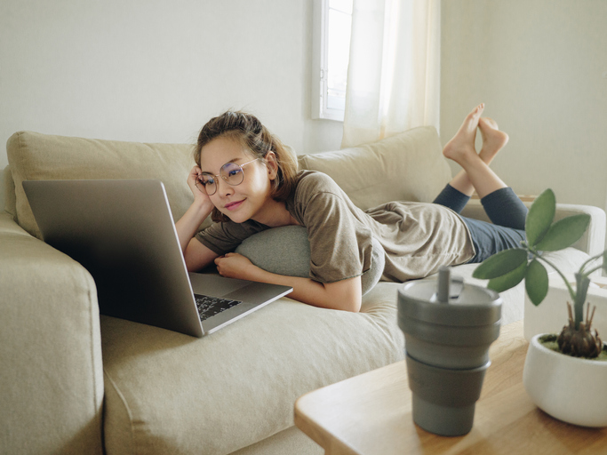 Teenager woman lying on sofa and using social network at home.