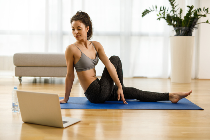 Woman in sportswear practicing yoga and watching tutorial lesson on laptop computer