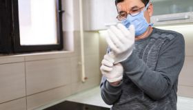 Senior man with pollution mask applying surgical gloves
