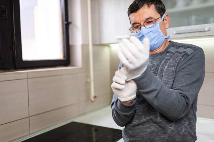 Senior man with pollution mask applying surgical gloves