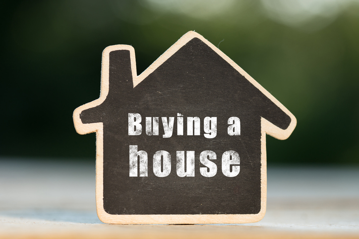 Buying a House written on the little house shape tag - real estate concept