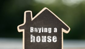 Buying a House written on the little house shape tag - real estate concept