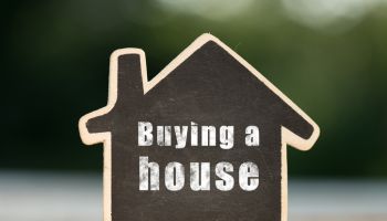 Buying a House written on the little house shape tag - real estate concept